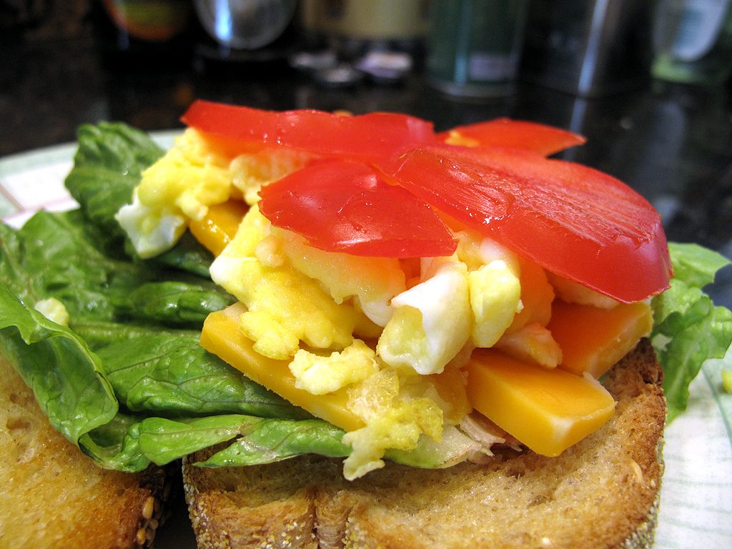 Cover the cheese with scrambled egg and cap with tomatoes