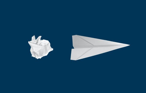 a paper ball next to a paper plane