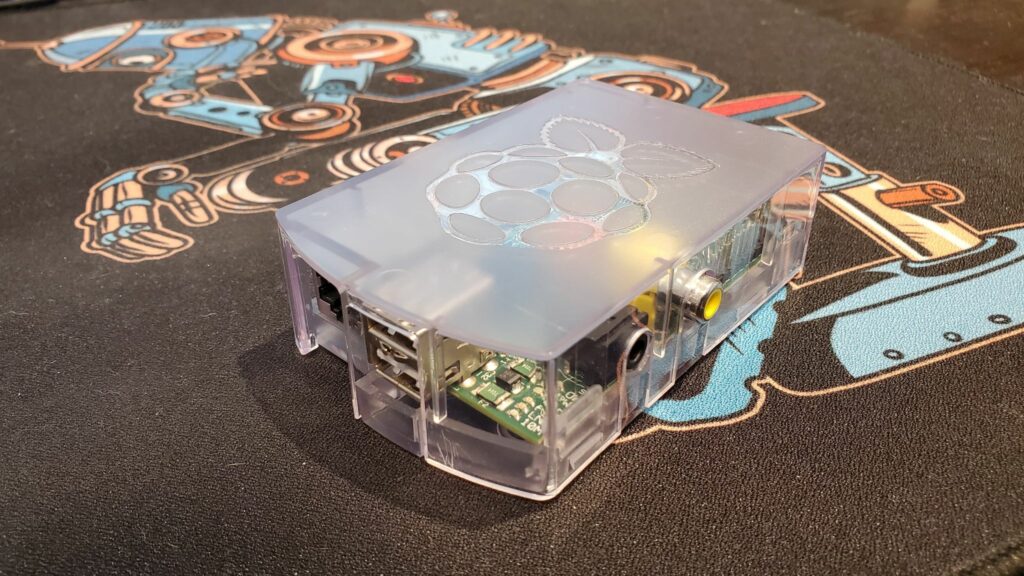 Raspberry Pi in a plastic casing, resting on an ornate jumbo mousepad.